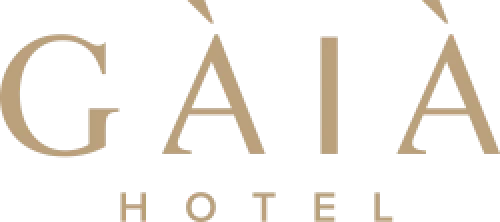 Tulisan "GĀIÀ HOTEL" tertulis dengan huruf elegan berwarna emas, menonjolkan identitas tempat penginapan yang mewah di latar belakang sederhana dan bersih.